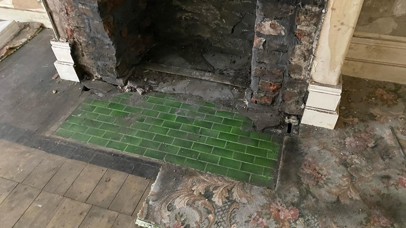 A fireplace opened up - green tiles and arches